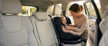 Madre colocando a su bebé en la silla de coche giratoria My Babiie i-Size Spin